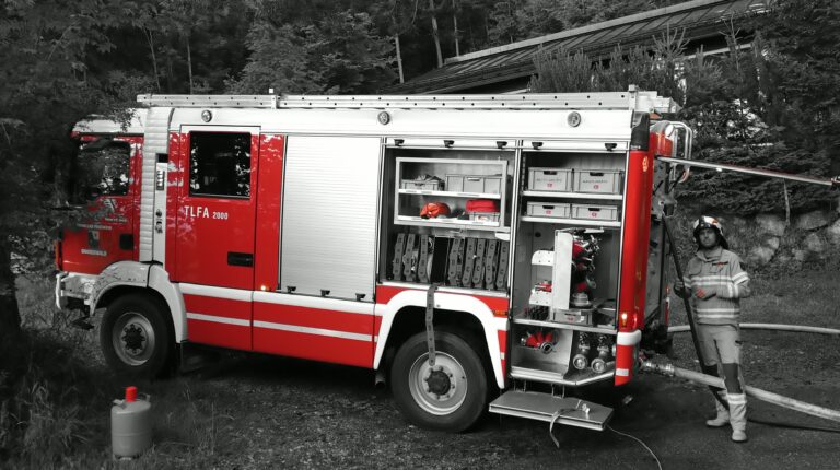 Rotes Einsatzfahrzeug TLF auf schwarz-weißem Hintergrund während einer Übung