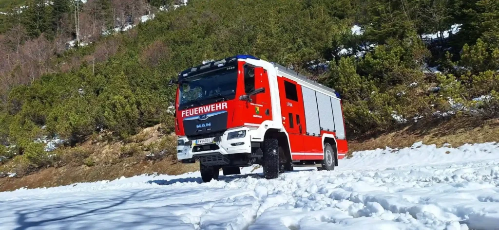 Einsatzfahrzeug LFB-A auf verschneiter Wiese vor bewaldeten Berghang in schräger Frontansicht